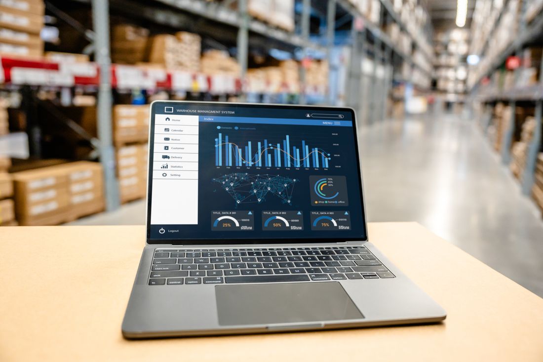 A laptop showing an operations dashboard on a table in a warehouse aisle
