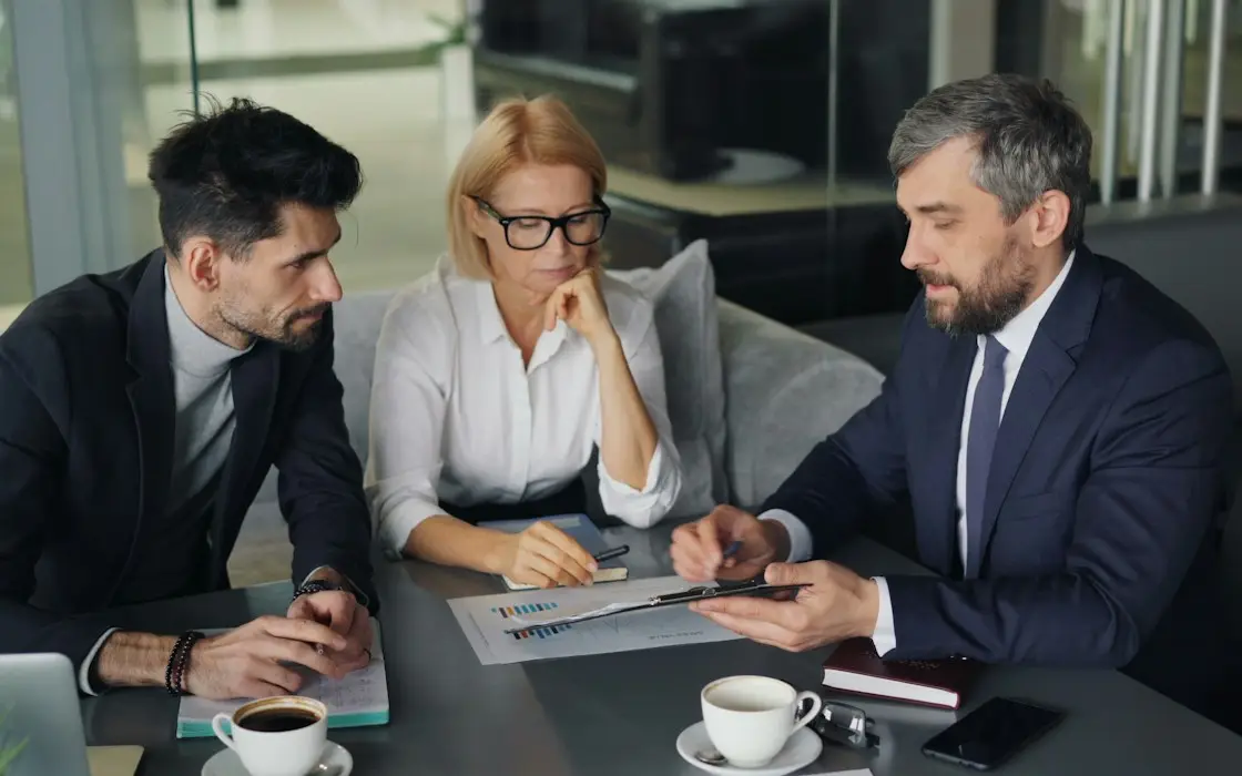 Three colleagues reviewing financial reports at a conference table