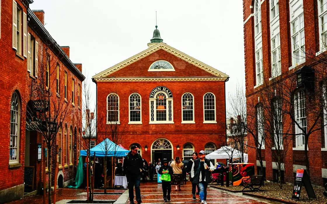 People walking past a red brick town hall on a city square